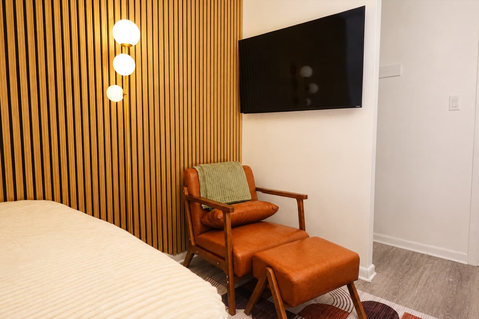 Furnished studio with ensuite bathroom at Amsterdam Place, Upper West Side NYC — leather lounge chair, ottoman, and wall-mounted TV