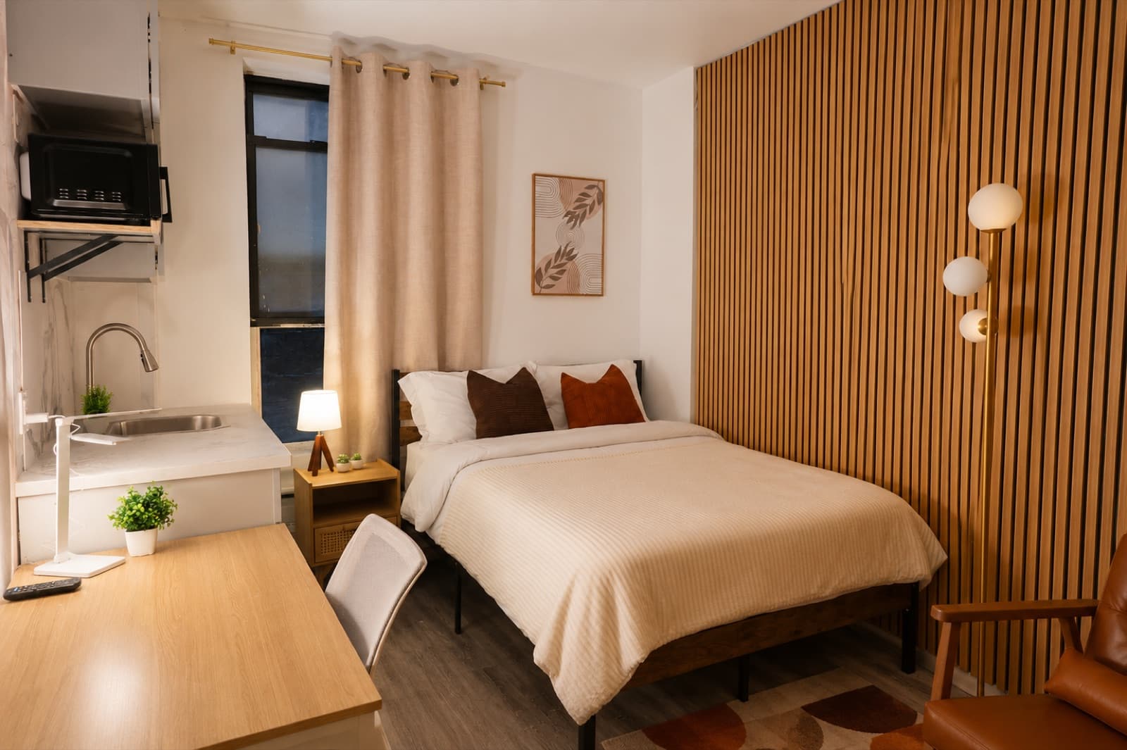 Furnished studio with private shower at Amsterdam Place, Upper West Side NYC — full studio with bed, workspace, and floor lamp