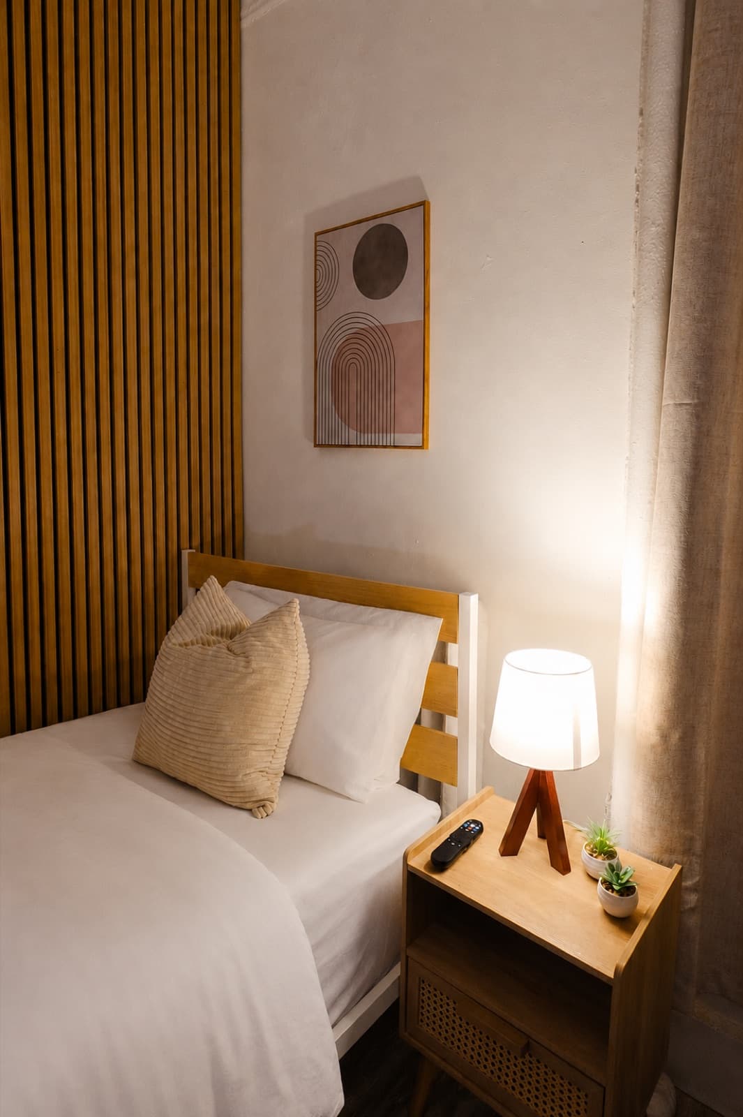 Private furnished room at Amsterdam Place, Upper West Side NYC — bed and rattan nightstand with a framed print