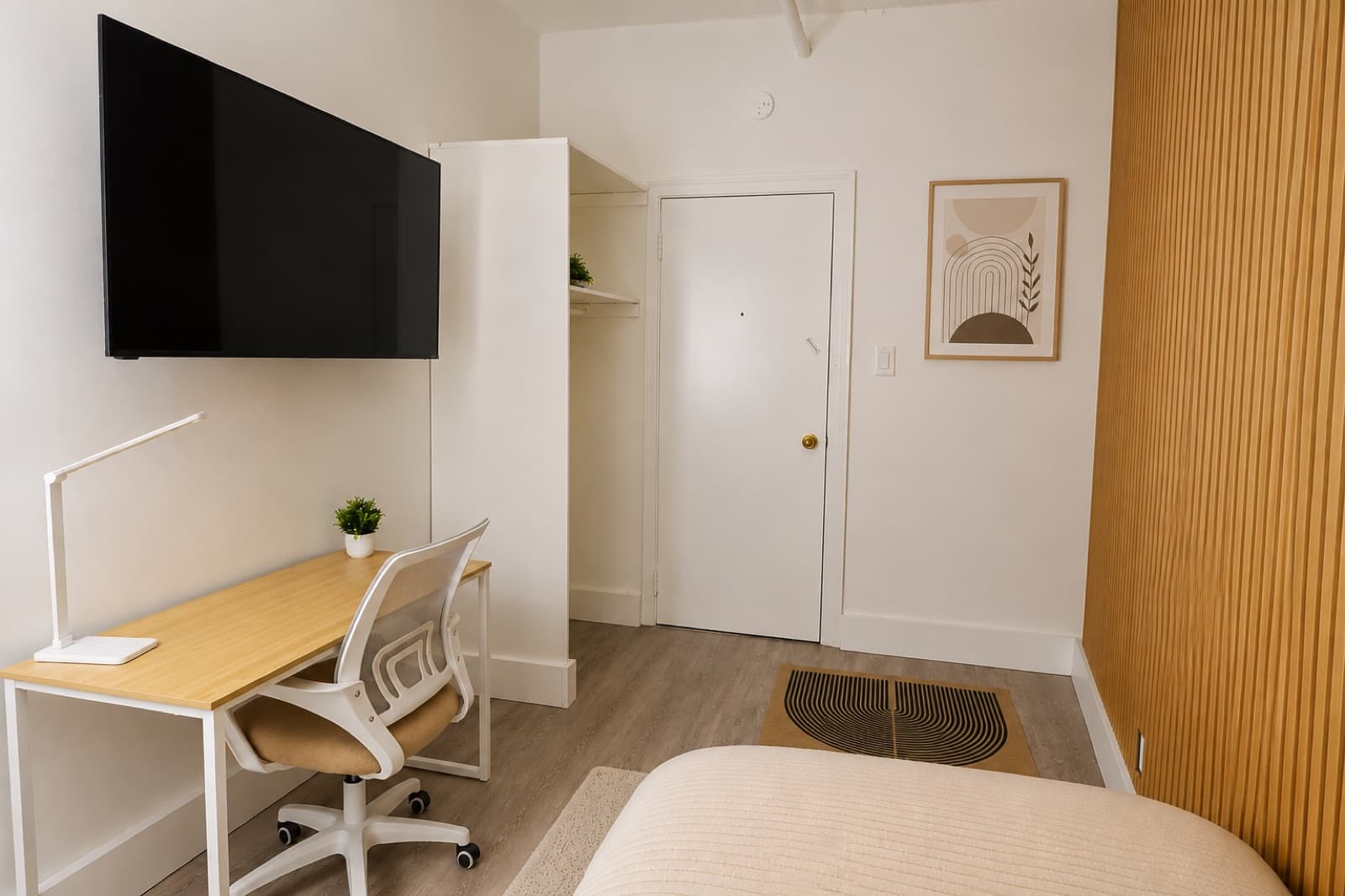 Private furnished room at Amsterdam Place, Upper West Side NYC — desk, doorway, and oak slat accent wall