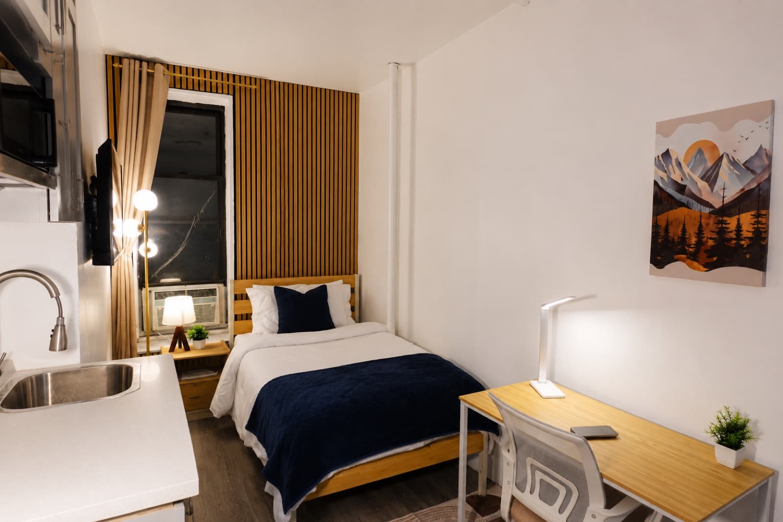 Deluxe furnished room at Amsterdam Place, Upper West Side NYC — twin bed, workspace, and framed landscape print